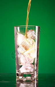 喝饮料在绿色背景上倒玻璃中的苏打水起泡图片