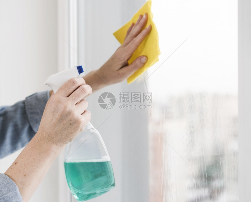 背部妇女清洗窗口的侧边视图清洁器液体图片