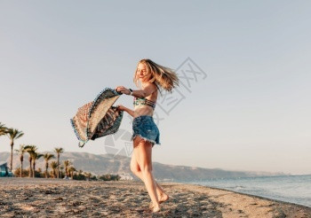 海滩微笑女人在波浪上跑着围巾在沙滩上放松快乐美丽图片