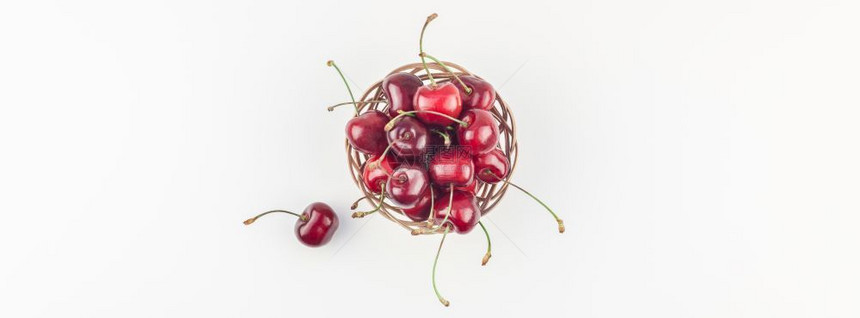 有创造力的为了长宽横幅在小圆篮子上盛满新鲜成熟樱桃带复制空间孤立的白色背景和最起码的风格用于文字或食物设计的夏季乐趣和健康饮食模图片