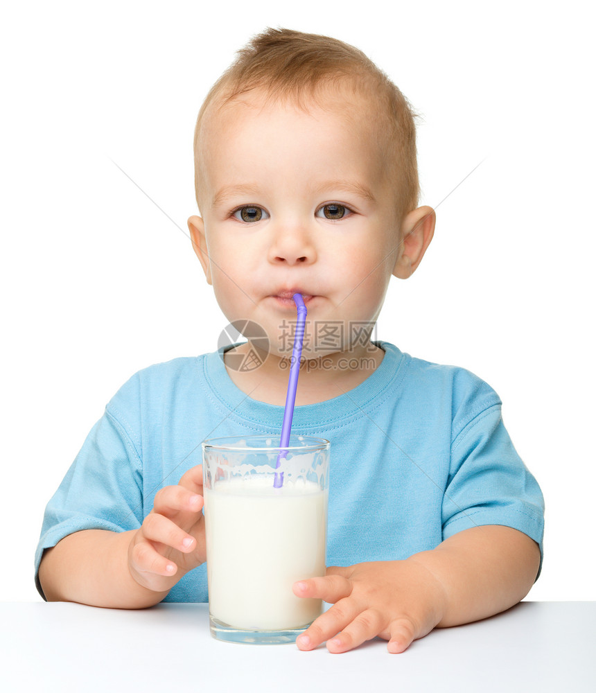 衬衫年轻的人类可爱小男孩坐在桌边子上用稻草喝牛奶在白上面被孤立图片