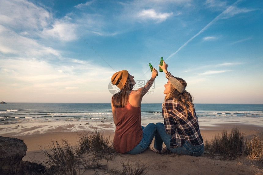 坐着的派对在海岸线上为友情敬酒的两位最好朋友谊图片