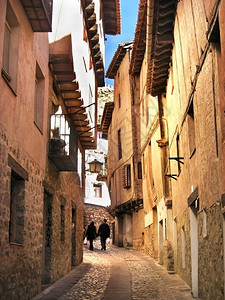 木头老的镇在西班牙街上行走的情侣周围有橙色浪漫建筑图片