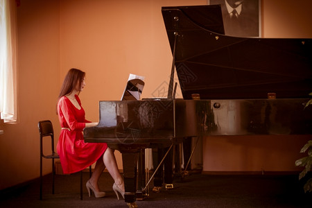 床单钢琴家穿红裙子的女人在弹大钢琴教育图片