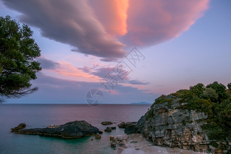 海岸景在一个小岩石海滩上度过的夏天夜晚多彩云日落在小岩滩上黄昏图片