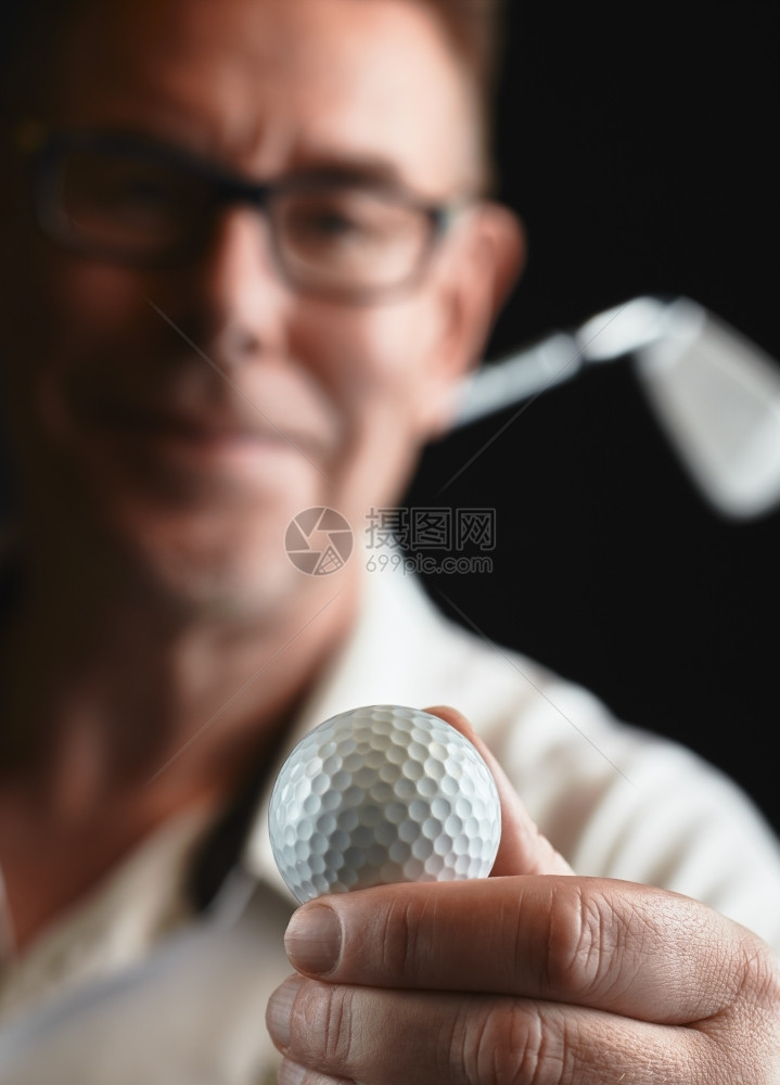 身穿白衬衫的成熟男子高尔夫球手握着肩膀上是铁高尔夫俱乐部专注于球摄影棚拍黑色背景白种人保持相机图片