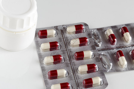 药片泡罩包装和白色药丸瓶背景中的药片泡罩包装和白色药片瓶红的处方药店图片