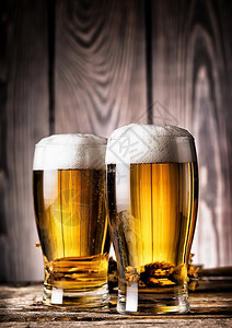 两杯木质背景上带泡沫的淡啤酒两杯带泡沫的淡啤酒食物桶背景图片