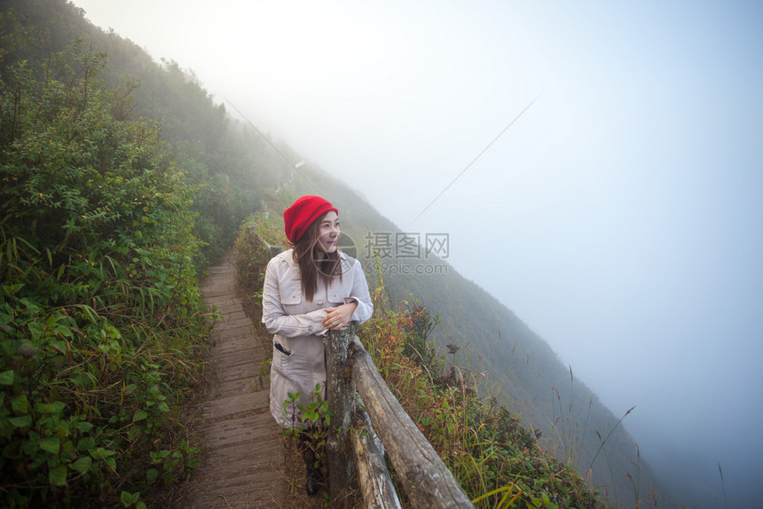 女旅行早晨站在悬崖边的年轻女子俯视山上雾泰国图片