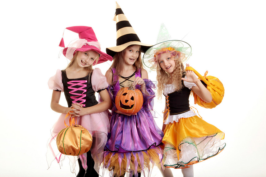三个美丽的微笑小女孩长发在彩色服装中看着镜头与诡计或处理袋和杰克奥斯柯绿灯露齿庆祝活动颜色图片