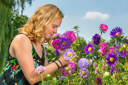 在花园里闻着夏香味的年轻荷兰女红发姑娘花朵士紫色的高清图片