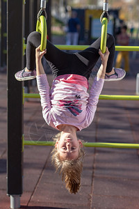 健康乐趣活动年轻女孩在体操圈上锻炼运动在游乐场上颠倒站在外边的姿势图片