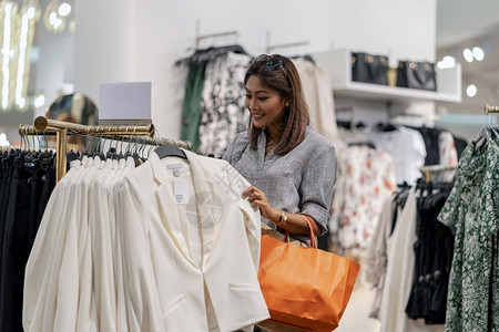 开心的亚洲女在商店里选择衣服在省中心采取快乐的行动服装人顾客图片