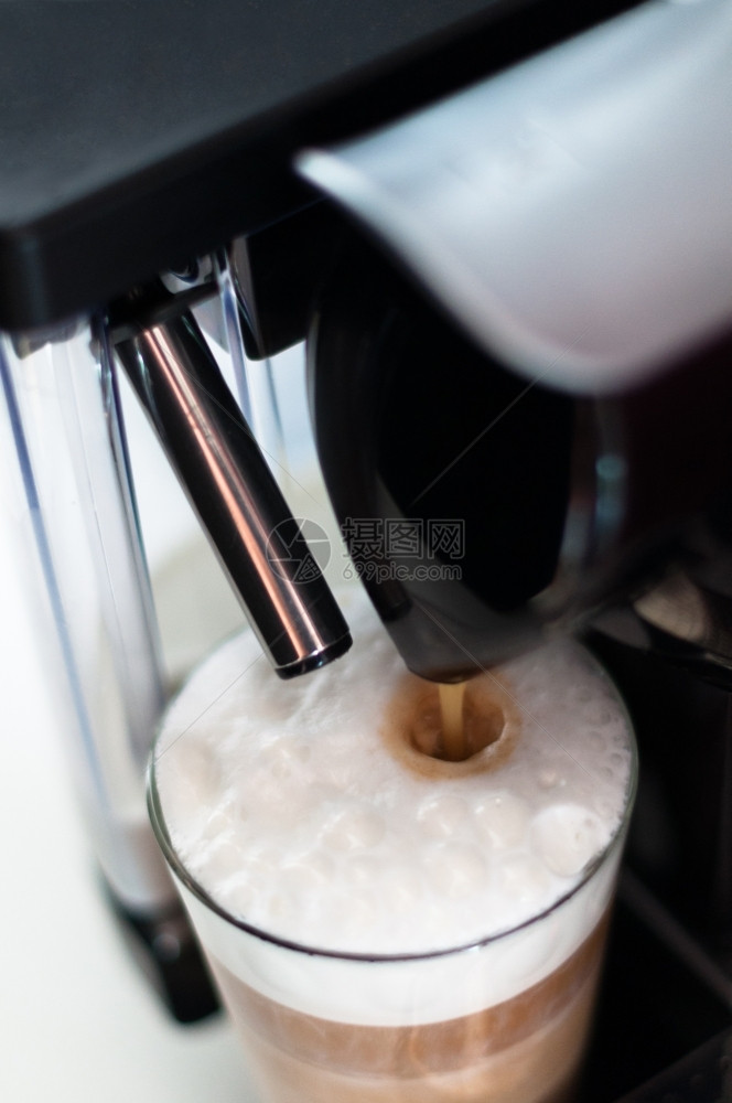 满的制作者现代咖啡机在一杯满牛奶的子里加咖啡图片