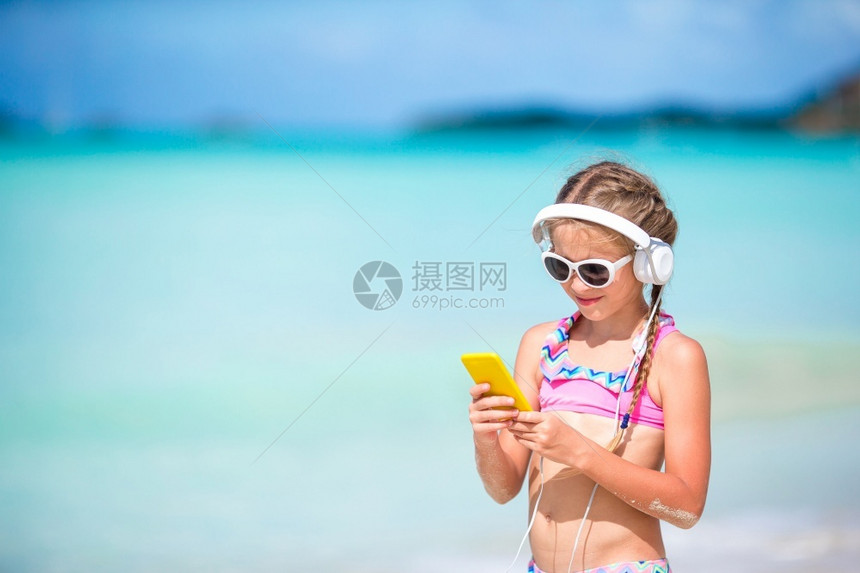 加勒比海享受经过小女孩在海滩上用耳机听音乐小可爱女孩聆听音乐背景海的歌声小可爱女孩图片