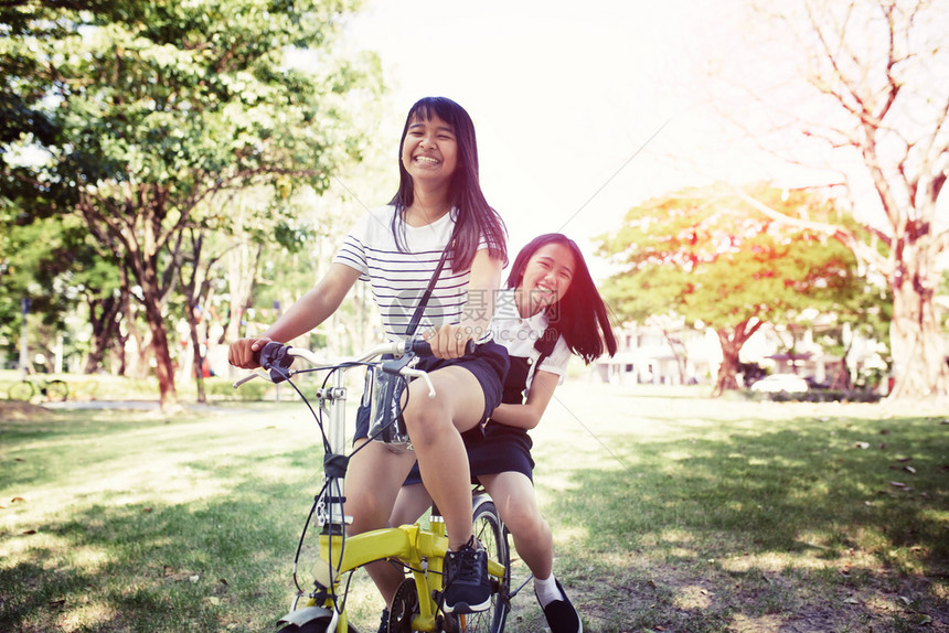 愉快在普尔比克公园骑自行车的亚裔青少年轻的乐趣图片