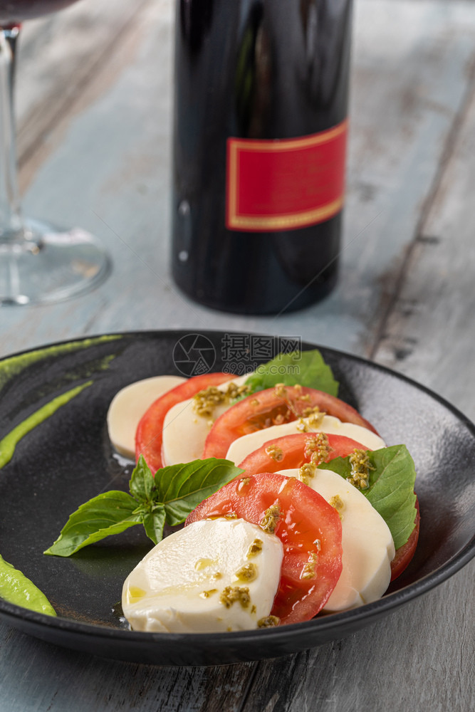 新鲜意大利口罩羊毛沙拉其中含有马扎里拉和西红柿在黑盘意大利口罩后加沙拉美味的玫瑰可口图片