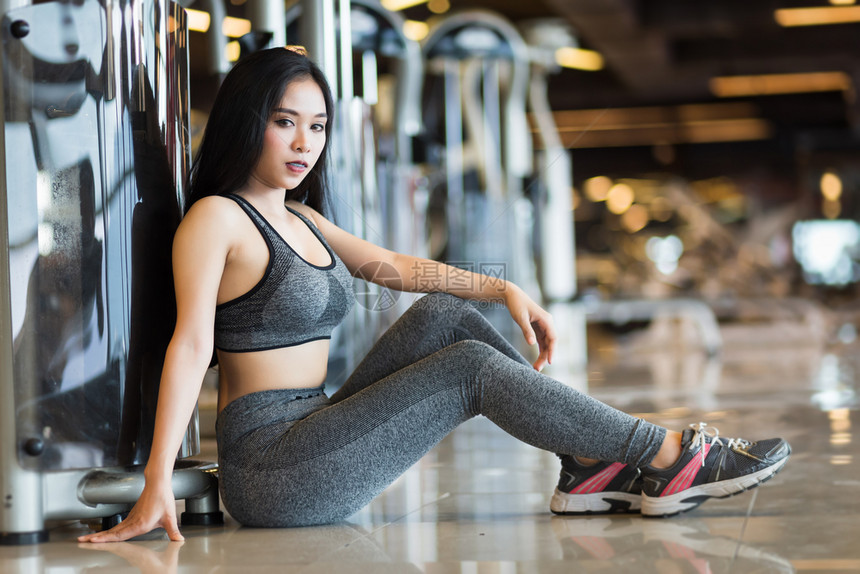 锻炼时尚坐着参加体操室内健身俱乐部和康俱乐部的亚洲妇女有运动设备具健身背景体育锻练设备图片