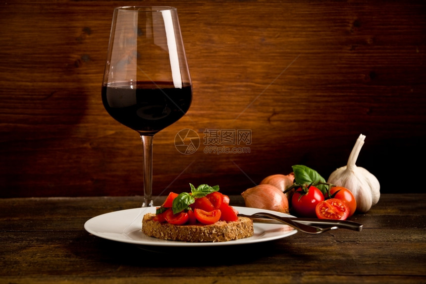 樱桃第一的切割Bruschetta美味的开胃菜和木制餐桌上红酒杯的照片图片