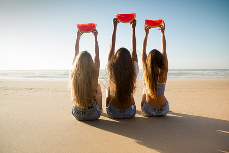 沙滩上举着西瓜的女孩们图片