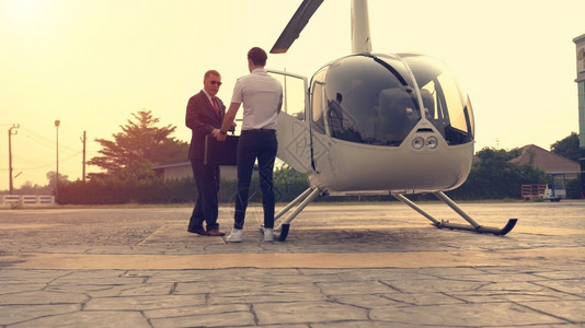 商人和飞行员在停靠点上小型私人直升机附近谈话的驾驶员和飞行机队长图片