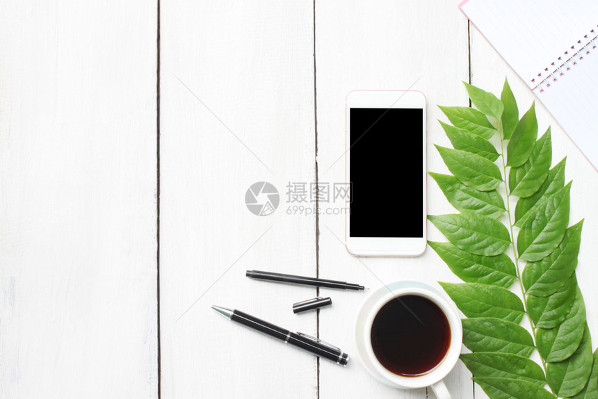 带有智能手机用品和咖啡杯的顶端白色木制办公桌并有供您使用的复制空间设计纸白色的平坦图片