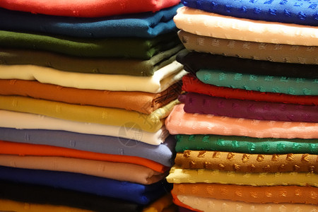 丰富多彩的在一个摊间里用许多不同颜色的布和料堆叠在一起衬衫桩图片