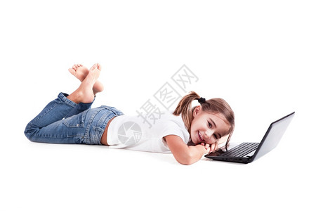 美丽的童年现代小女孩躺在地板上用笔记本电脑工作图片