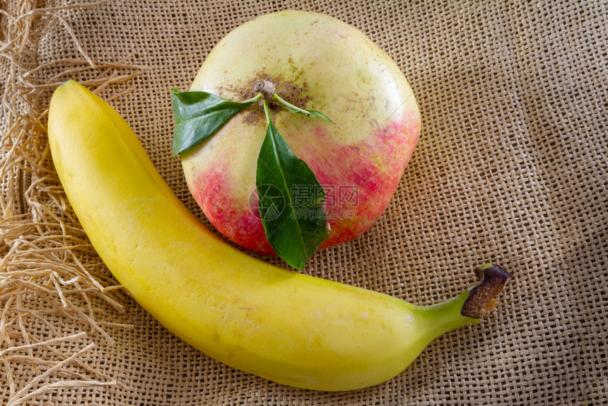 一份成熟的石榴和一份棕色麻布上香蕉这是传统有机食品概念示范方案红色的织物棕图片