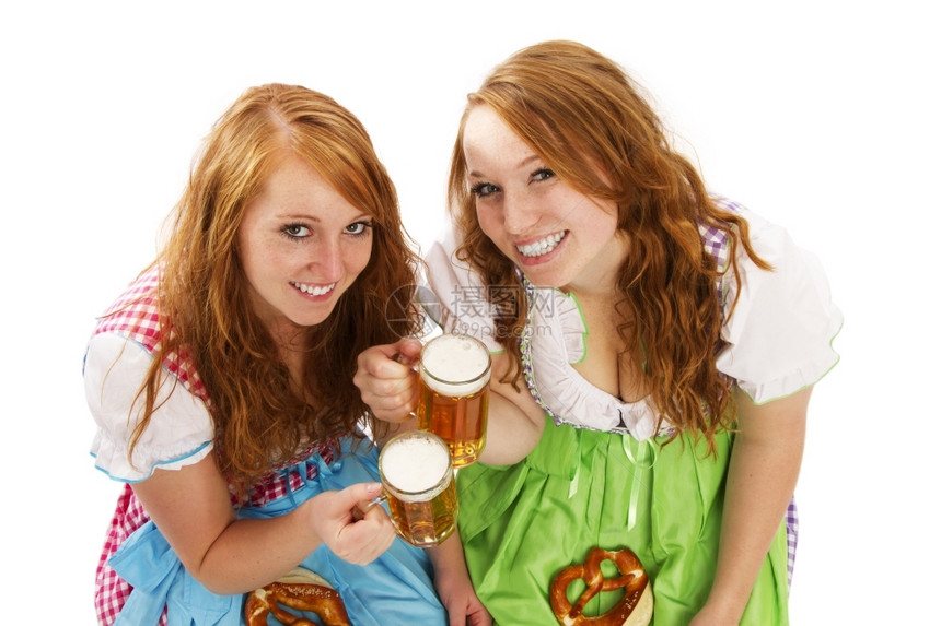 德国两个有啤酒的巴伐利亚女孩和两个带啤酒的巴伐利亚女孩和白底面的百日饼慕尼黑德语图片