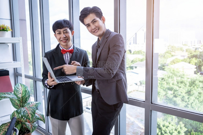 当代的青年亚洲商人和辅导私秘书助理男双和变者伙伴同时与笔记本电脑和办公室业务战略合作男技术图片