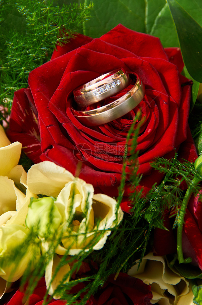 家庭仪式绽放带有玫瑰和戒指的婚礼花束图片