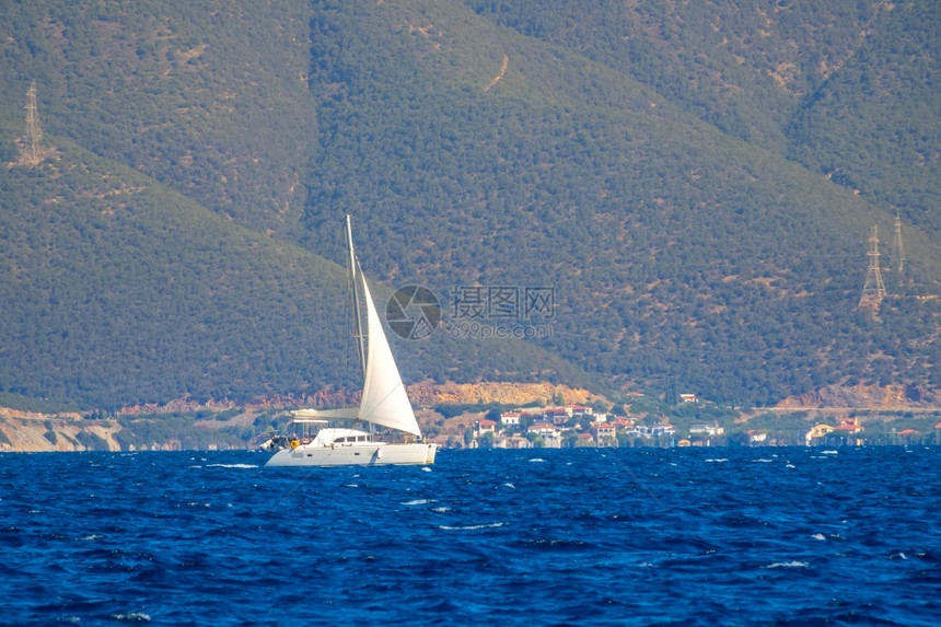 白游艇上高山与帆航行游艇和大型沿海山丘的航行中洋景岸图片