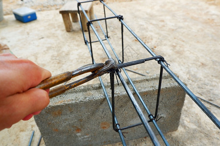 网格框架用钳子把铁钢丝捆绑起来建造倾灌波兰和横梁的建筑结构民事图片