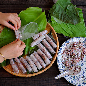 鸡蛋春卷叶子材料春天妇女在家里做春卷或香焦自制食物用肉填料米纸包装在绿叶背景上手滚越南鸡蛋卷背景