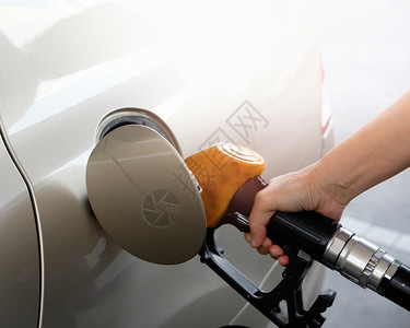 商业金色汽车正在加油站手持煤气泵中燃料喷嘴的油罐昂贵处理图片