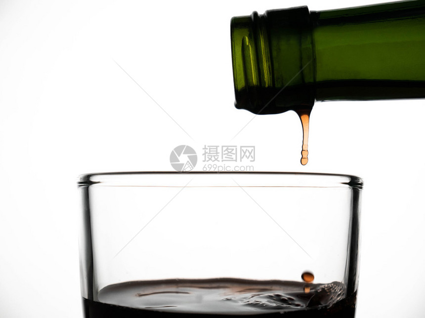 环境液体气泡从绿色瓶子倒到玻璃杯的果汁紧贴地从绿瓶子倒到白色背景上图片