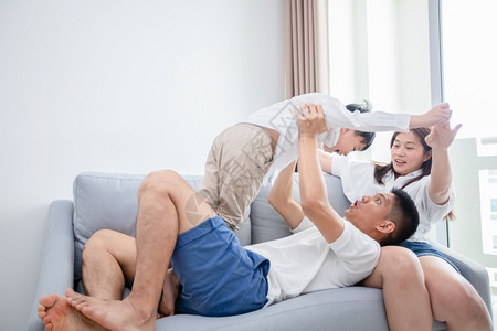 快乐的亚洲家庭与儿子一起在家沙发上玩和笑欢乐地共度节日女士孩室内的图片