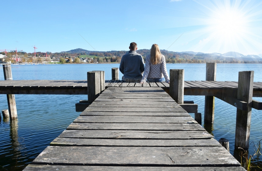 女孩在湖边木制码头的一对夫妇海岸线柴金图片