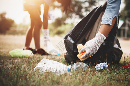 乐观的处理妇女用手捡垃圾塑料在公园打扫保护图片