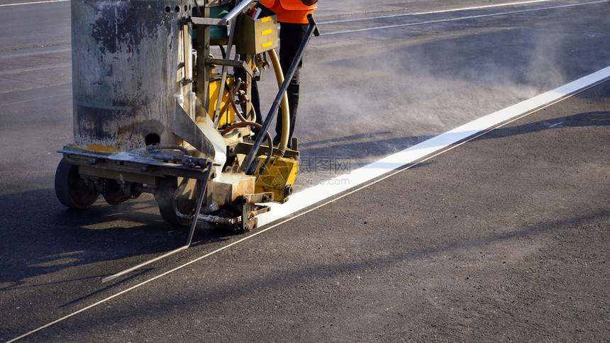 白色的工作在沥青路面铺有热塑料喷雾路标记机器的低路工在沥青面上用蒸汽和铁路横跨公线粉刷交通白修理图片