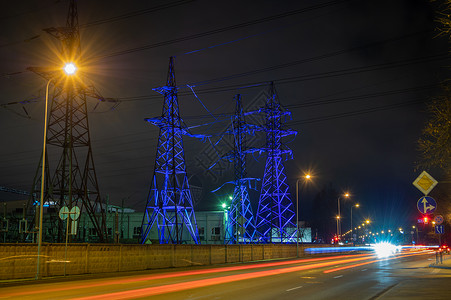 建造晚上城市高压塔在夜晚以蓝光照亮高电压塔街道灯光照射长的浅地期照射图片