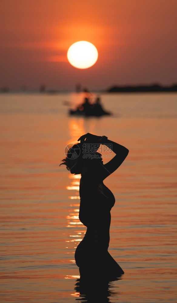 颜色金子日落的海洋视线太阳在橙色天空海面上女人站在沙滩上暮图片