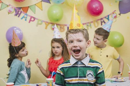 拿着气球恐龙脸帽快乐的男孩与朋友一起庆祝生日父亲背景