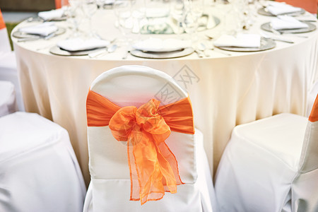 派对晚餐白色的婚宴餐桌上面有彩色白发罩椅和橙风管沙司图片