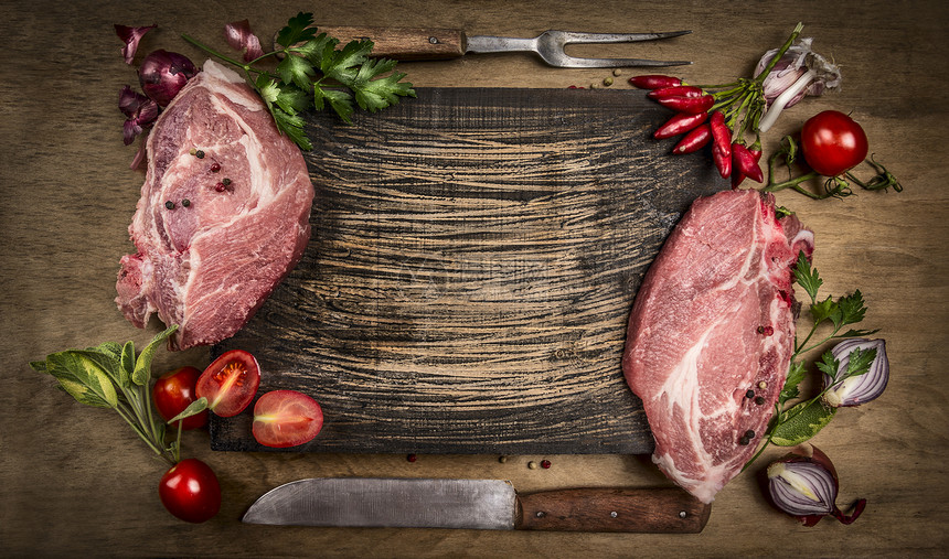 木制的生猪肉排配有厨房工具新鲜调料和在生木背景顶视图文字框架上烹饪的原料超额食用图片