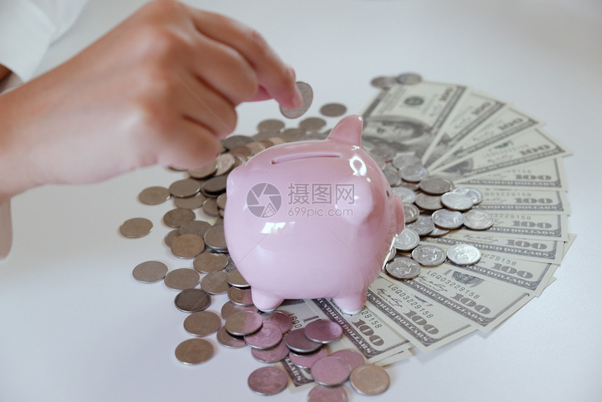 桌子增加人们用硬币和钱把放进小猪银行收入图片