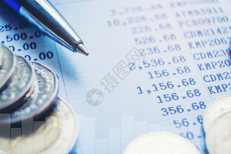 股票平衡资产商业文件纸上的笔和硬币背景图片