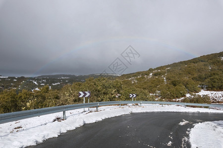 驾驶山路在冬季的阴云多天上背景是彩虹地平线自然图片