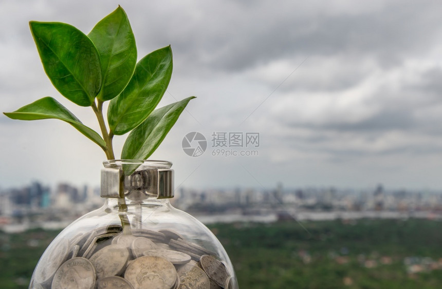 储蓄成功植物在硬币堆上生长的树苗在城市景观背的玻璃瓶中业务增长的象征和省钱的投资理念文本输入空间选择焦点图片